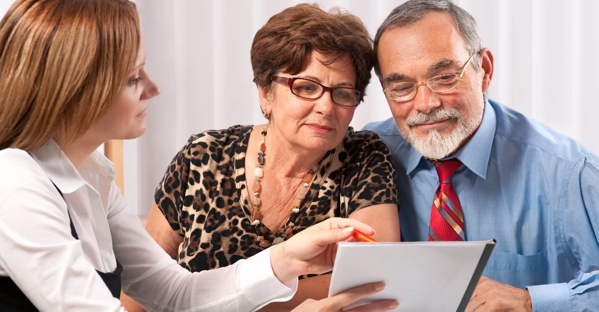 Conseillère funéraire présentant un contrat d'assurance prévoyance à un couple de seniors